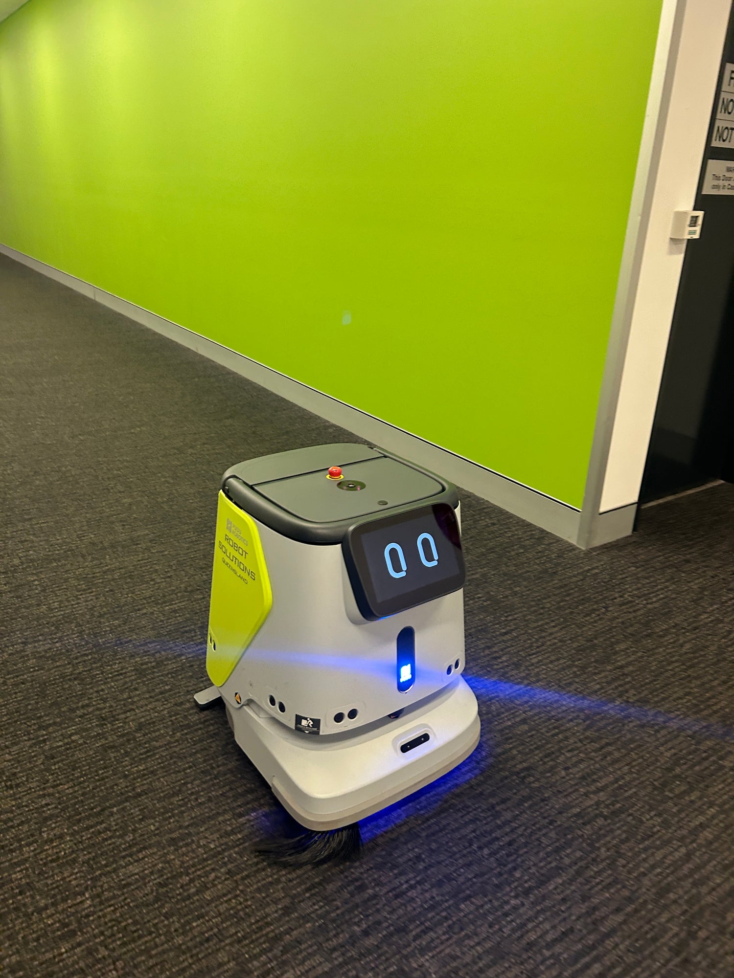 Pudu CC1 Robotic cleaning device on a carpeted floor with a green board in the background From Robot Solutions QLD