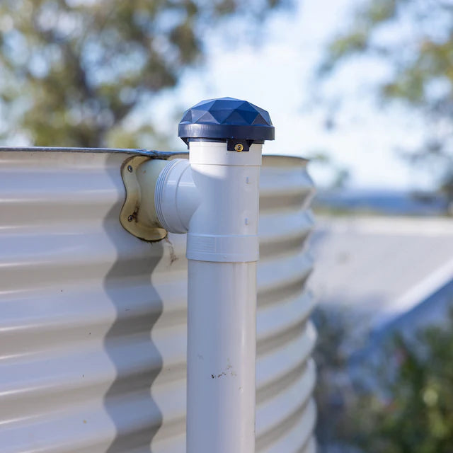 White pipe with blue cap on a corrugated metal surface, blurred natural background